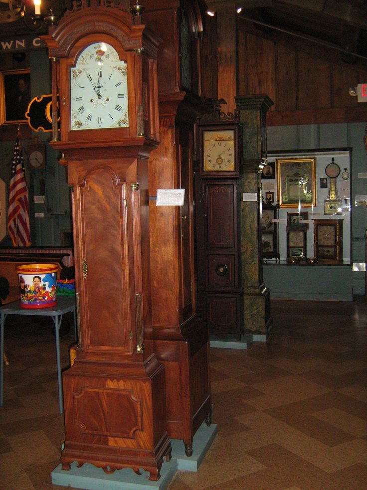 an antique grandfather clock on display in a room with flags and other items around it