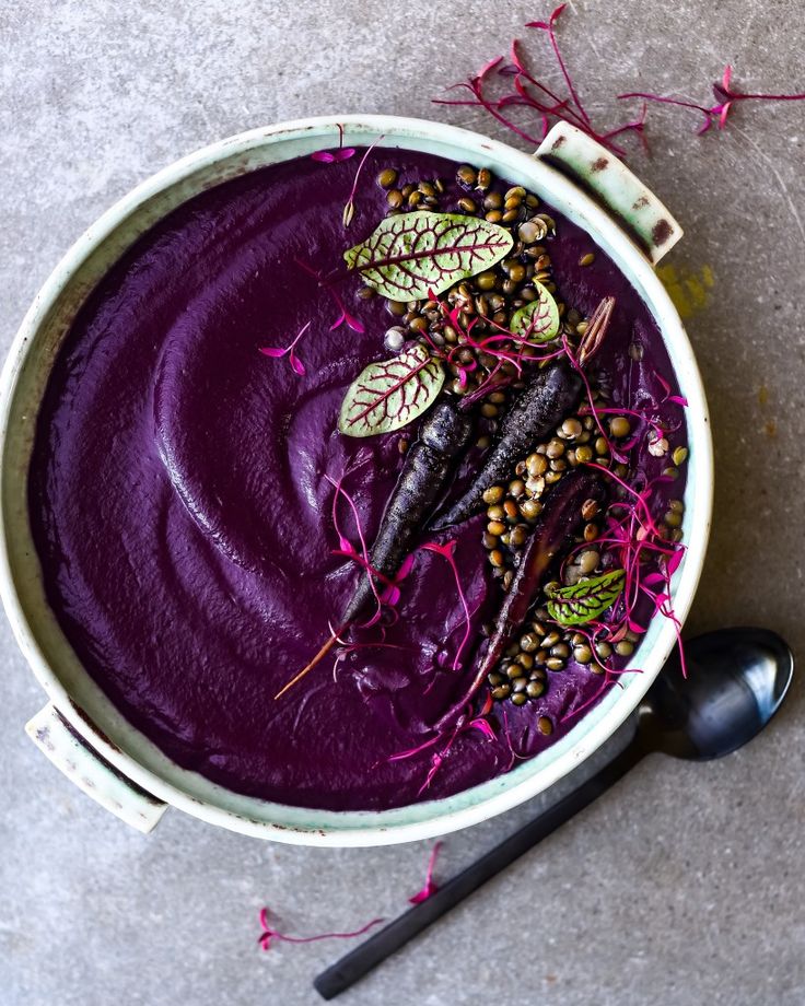 a bowl filled with purple food and garnished with leafy sprouts