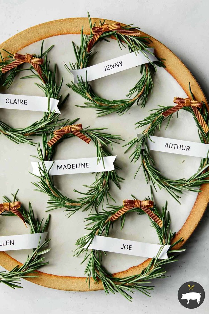 rosemary wreaths with name tags and pine cones on them, arranged in the shape of a circle