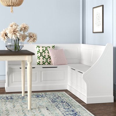 a room with a bench, table and flowers on the rug in front of it