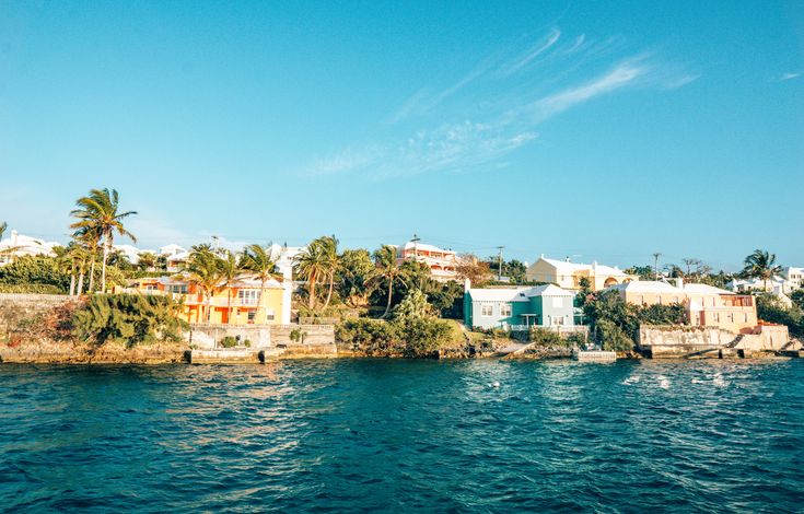 an island in the middle of water with houses on top and palm trees around it