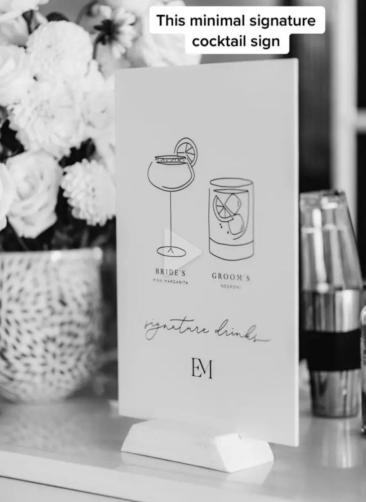 a cocktail sign sitting on top of a table next to bottles and glasses filled with drinks