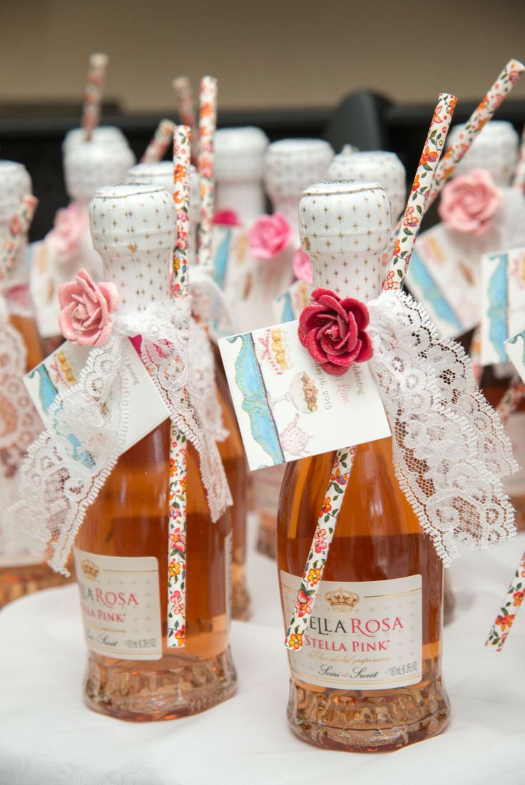 several bottles of rose wine are sitting on a table with lace and ribbons tied around them