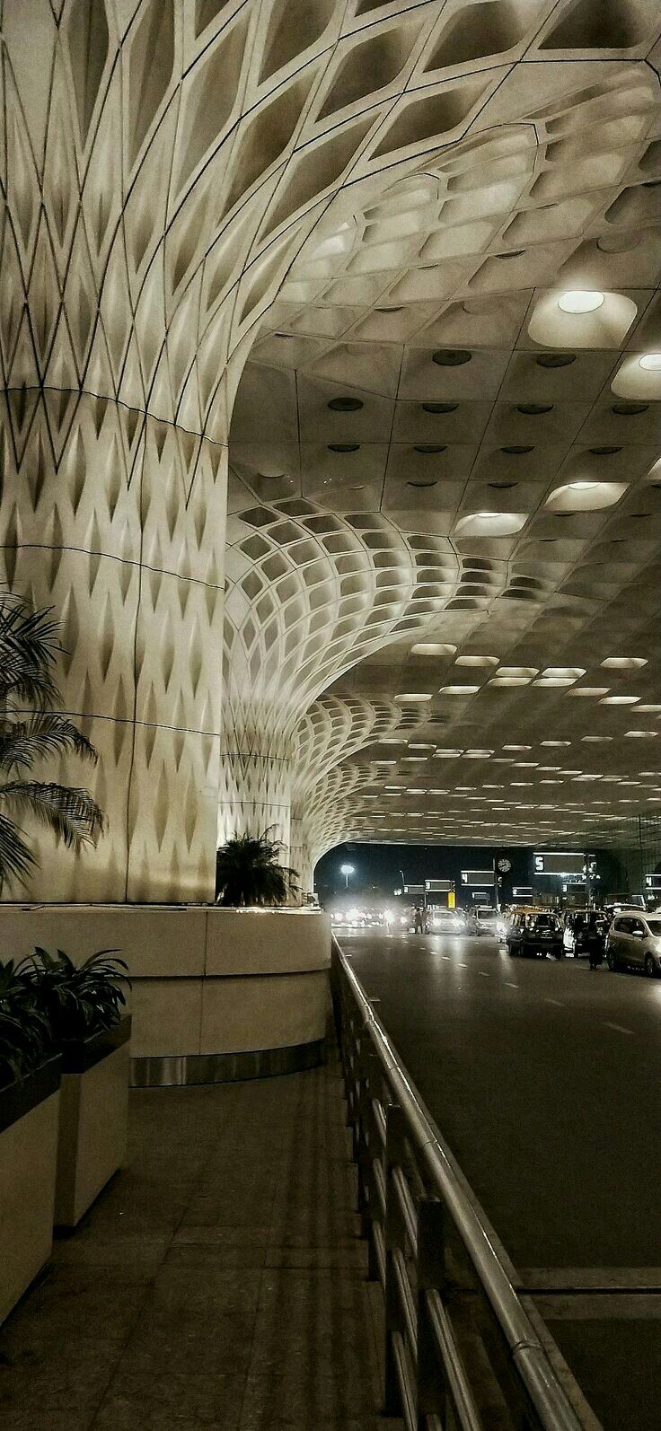 the interior of an airport with cars parked in front of it and palm trees on either side