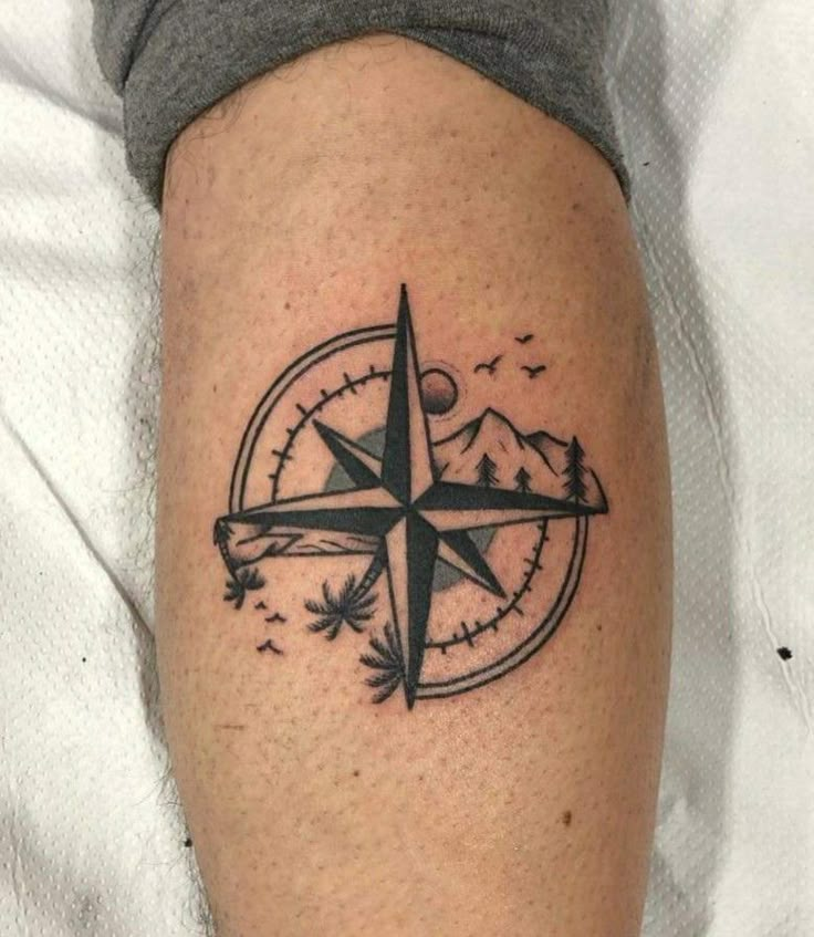 a black and white compass tattoo on the leg