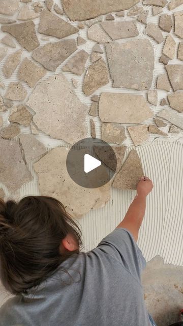 a girl is painting a stone wall with white paint