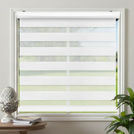 a window with white blinds in the corner next to a table and potted plant