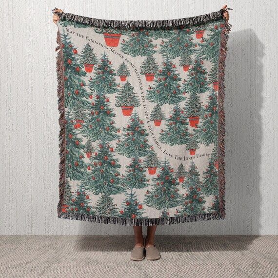 a woman standing in front of a christmas tree blanket