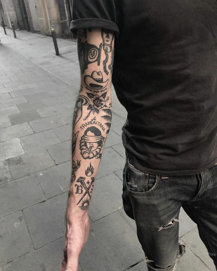 a man with tattoos on his arm walking down the street