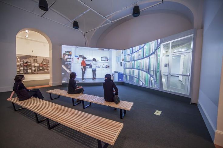 two people sitting on benches in an art gallery