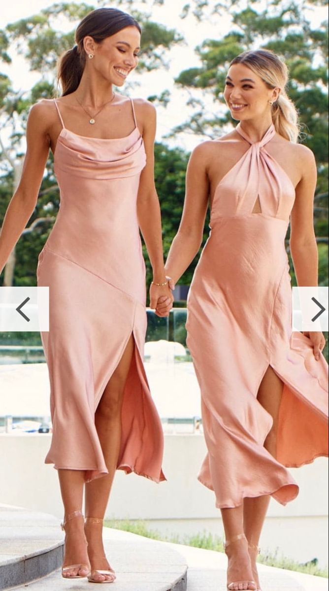 two women in pink dresses walking down the street together, one is holding her hand