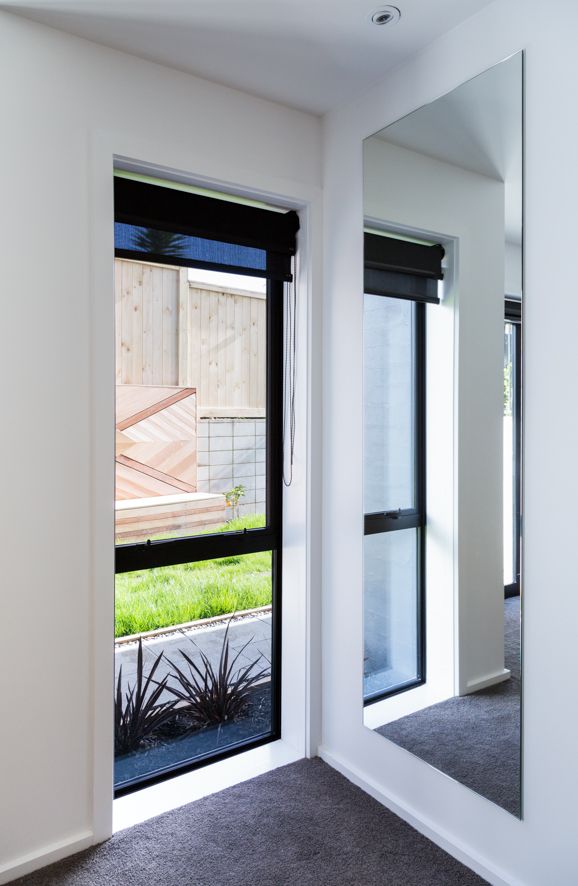 an empty room with a large mirror on the wall and plants in front of it