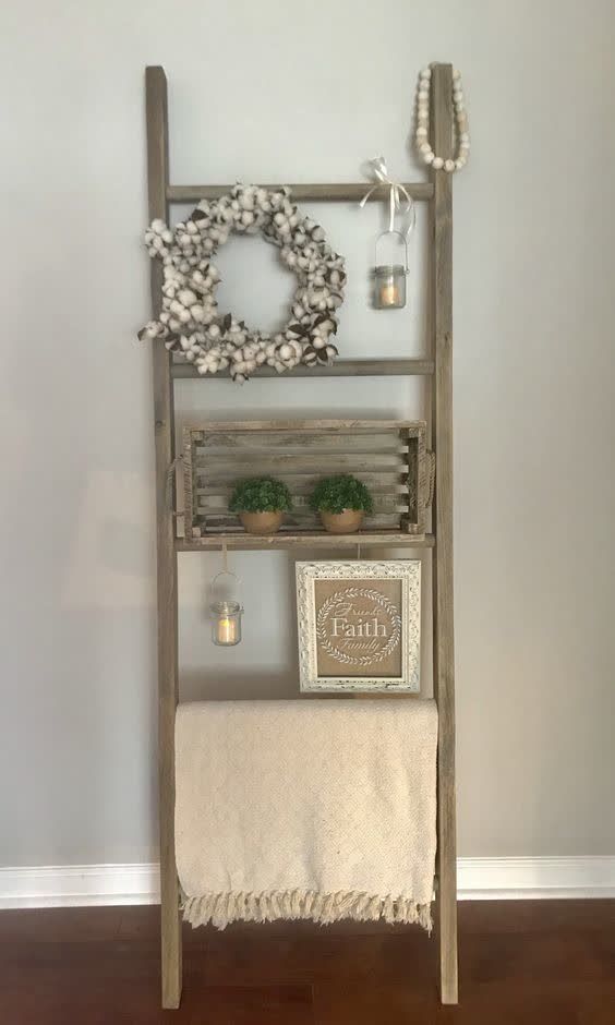 a wooden shelf with candles and wreaths on it next to a white towel rack