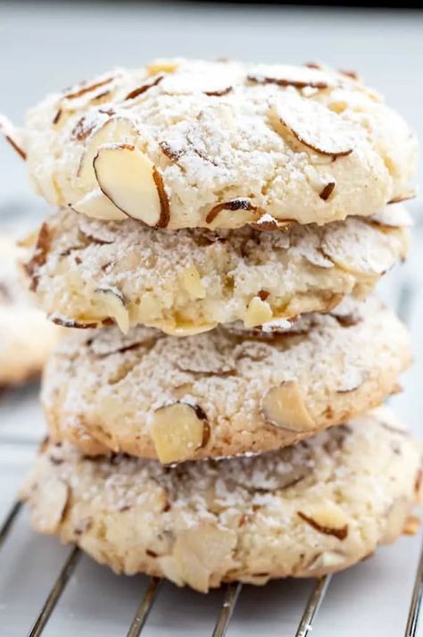 a stack of cookies sitting on top of a cooling rack with almonds and powdered sugar