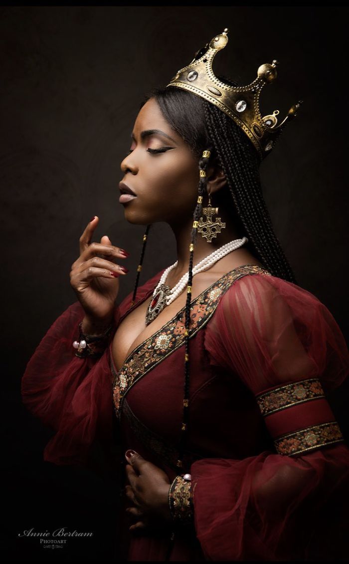 a woman in a red dress with a crown on her head and beads around her neck