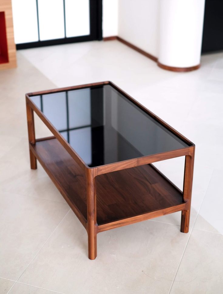 a coffee table sitting on top of a white floor next to a wall with windows