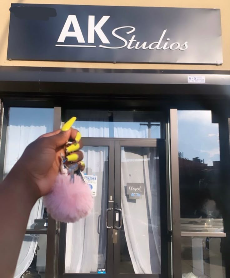 a person is holding a pink pom - pom in front of a building