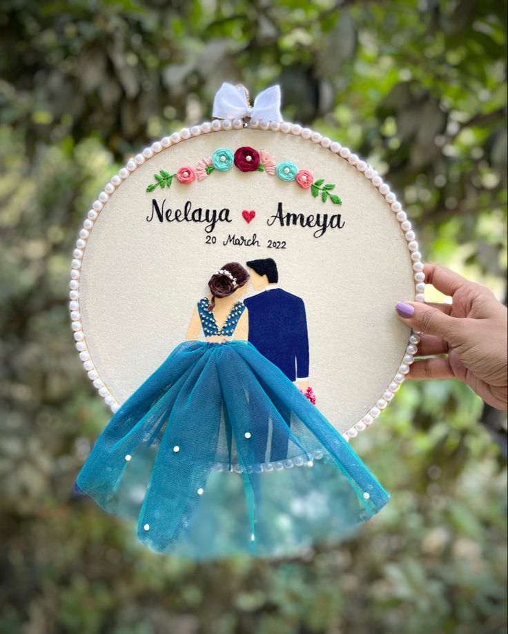 a hand holding up a wedding ornament with a bride and groom on it