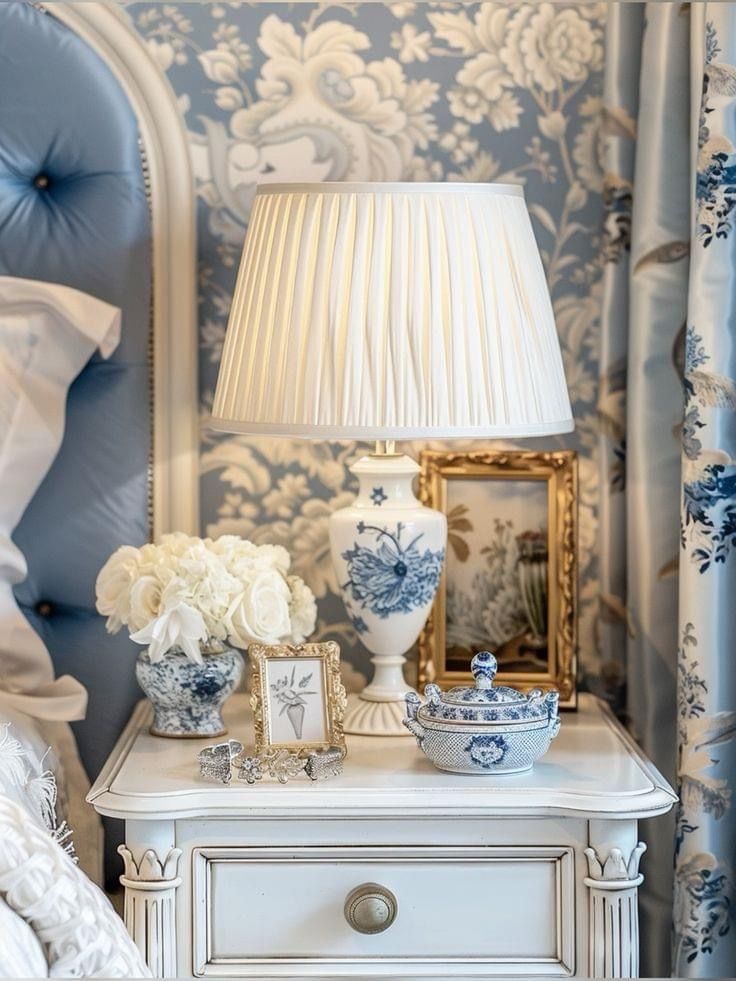 a blue and white lamp sitting on top of a table next to a bed in a bedroom