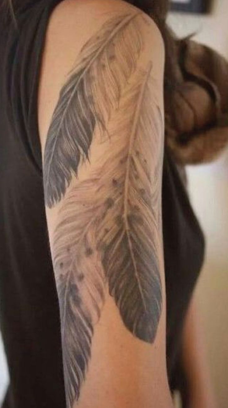 a woman with a tattoo on her arm has a feather design on it's arm