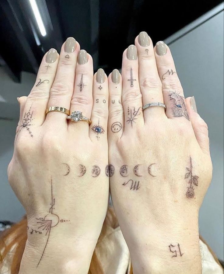 two women with tattoos on their hands are holding each other's hands in front of the camera