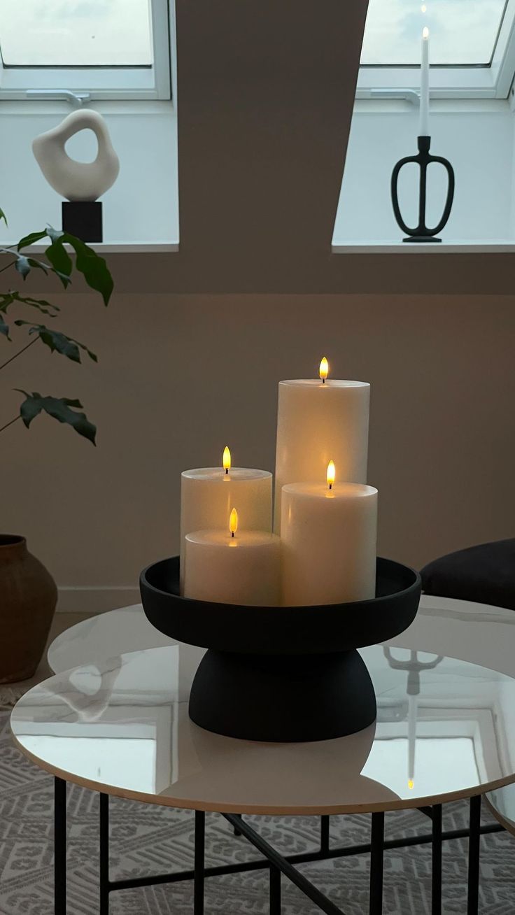 three lit candles sit on top of a glass table