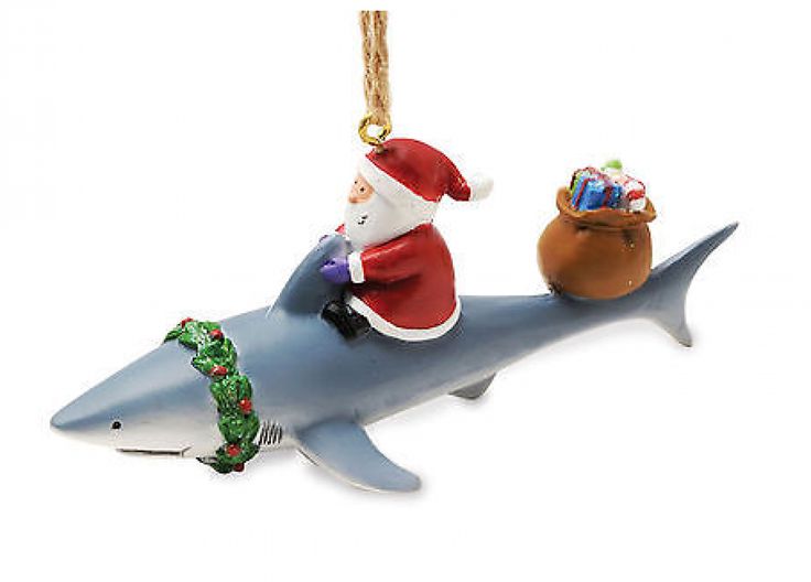 a christmas ornament featuring santa riding a shark with presents in its mouth and on the back