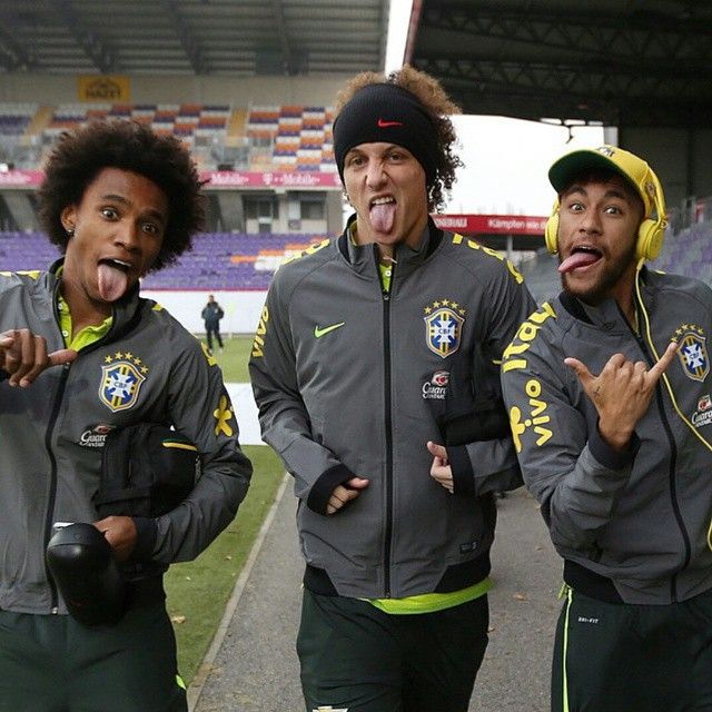 three soccer players are standing on the field with their tongue out and one is sticking his tongue out