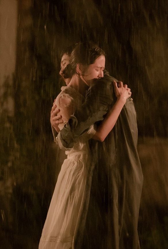 two people standing in the rain hugging each other