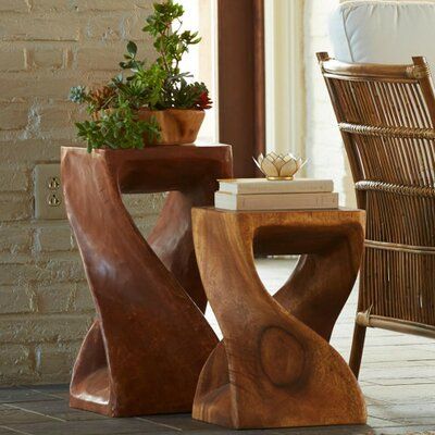 two wooden chairs sitting next to each other in front of a brick wall and potted plant