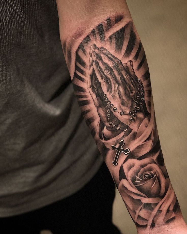 a man's arm with a cross and rosary on it, in front of a rose