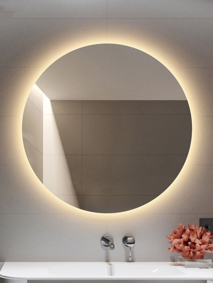 a bathroom sink with a round mirror on the wall above it and a flower in front of it