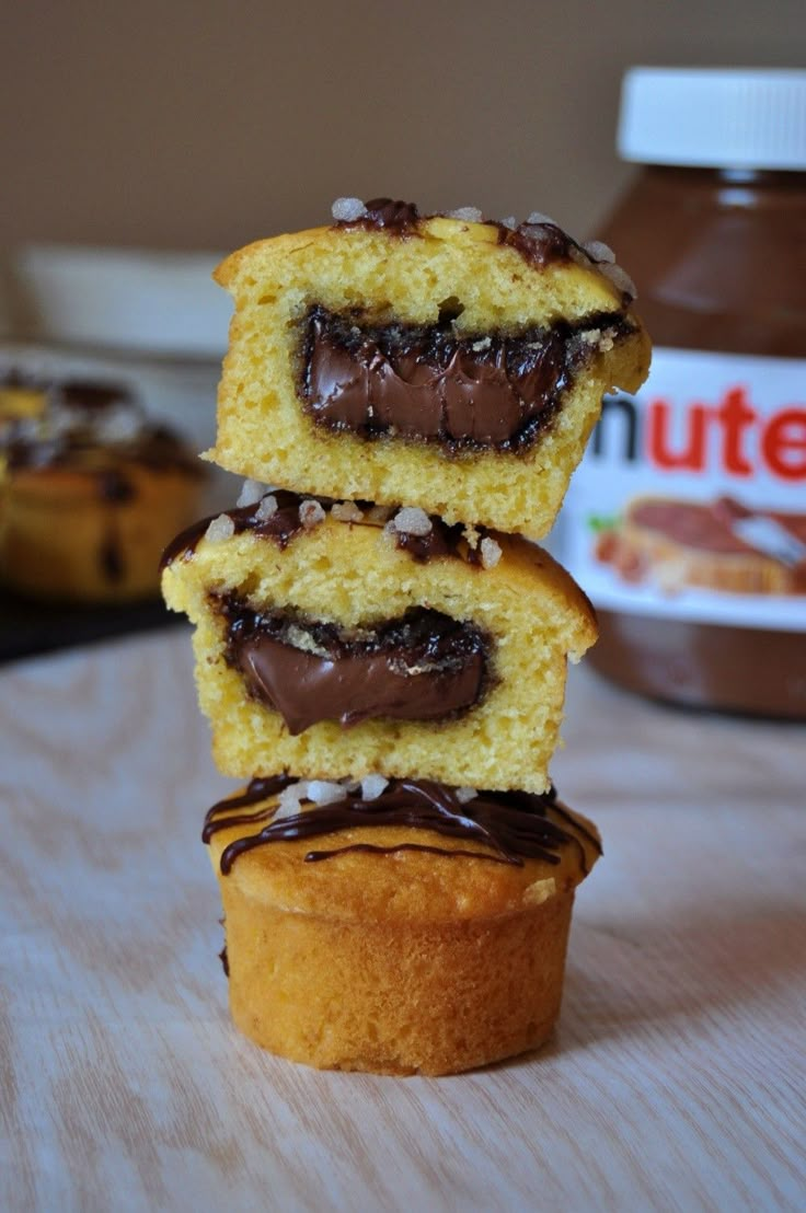 three cupcakes stacked on top of each other with chocolate frosting and nuts