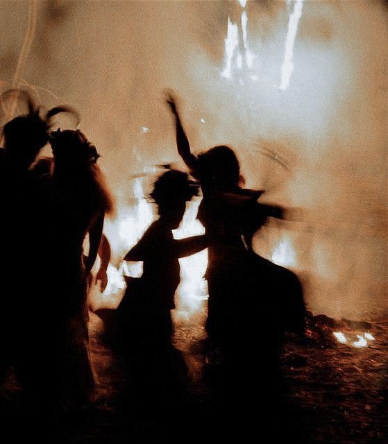 silhouettes of people dancing in front of a fire