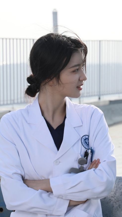 a woman wearing a white coat and holding a stethoscope in her hand