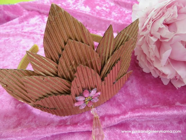 a pink flower sitting on top of a table next to a piece of cardboard paper