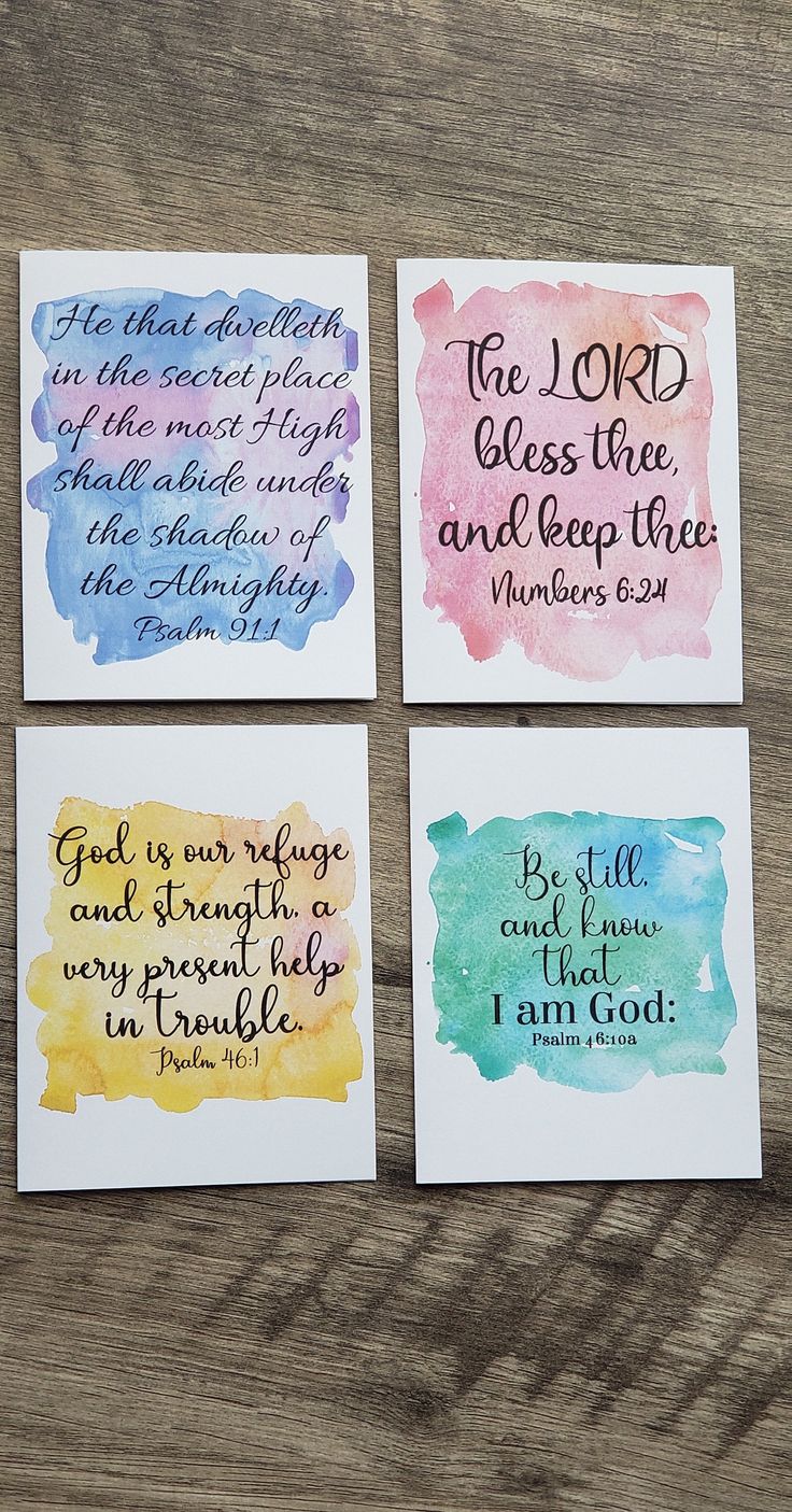 four watercolor cards with bible verses on them sitting on top of a wooden table