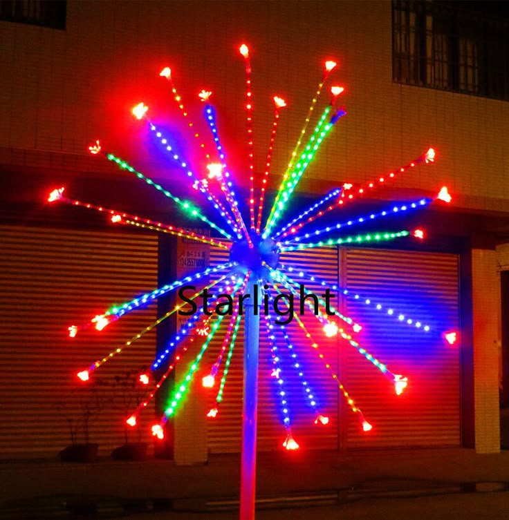 a pole with lights on it in front of a building and garage doors at night