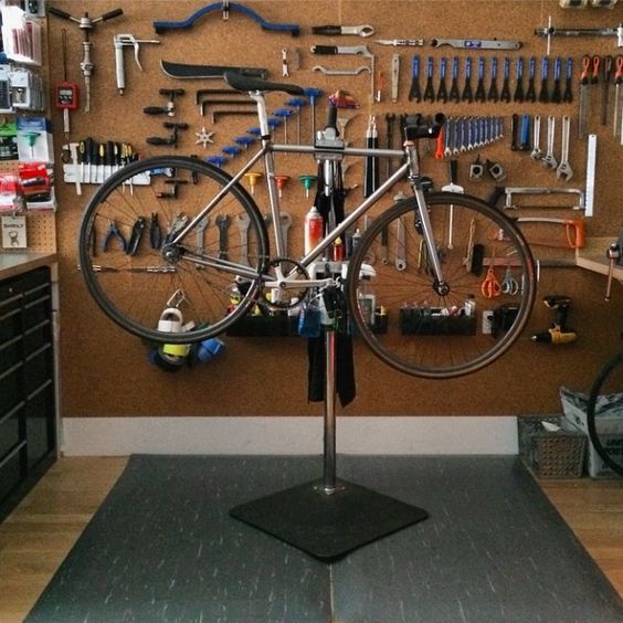 there is a bike that is on display in the garage with tools hanging from the wall