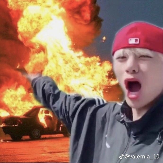 a young boy wearing a red beanie is screaming in front of a large fire