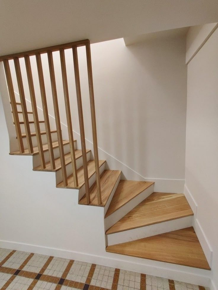 there is a stair case in the corner of this room with tile flooring and wooden handrails