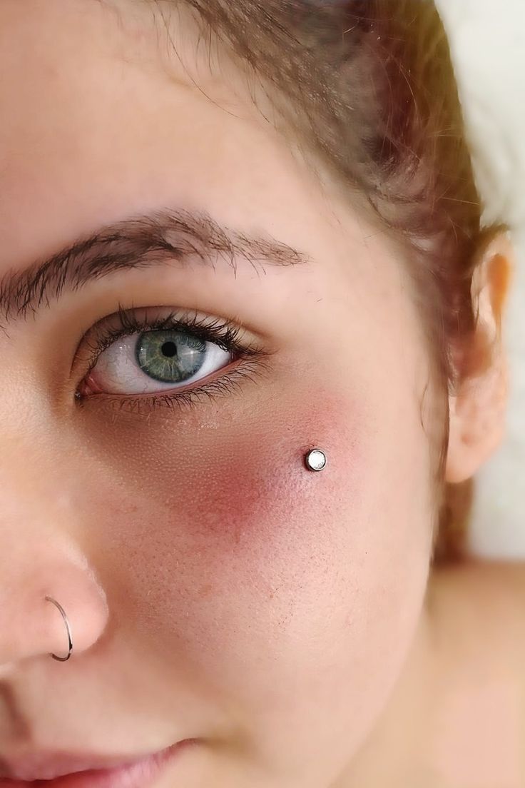 a woman with piercings on her nose looking at the camera