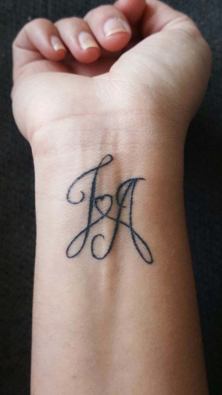 a woman's wrist tattoo with the letter f on her left hand and an initial in the middle