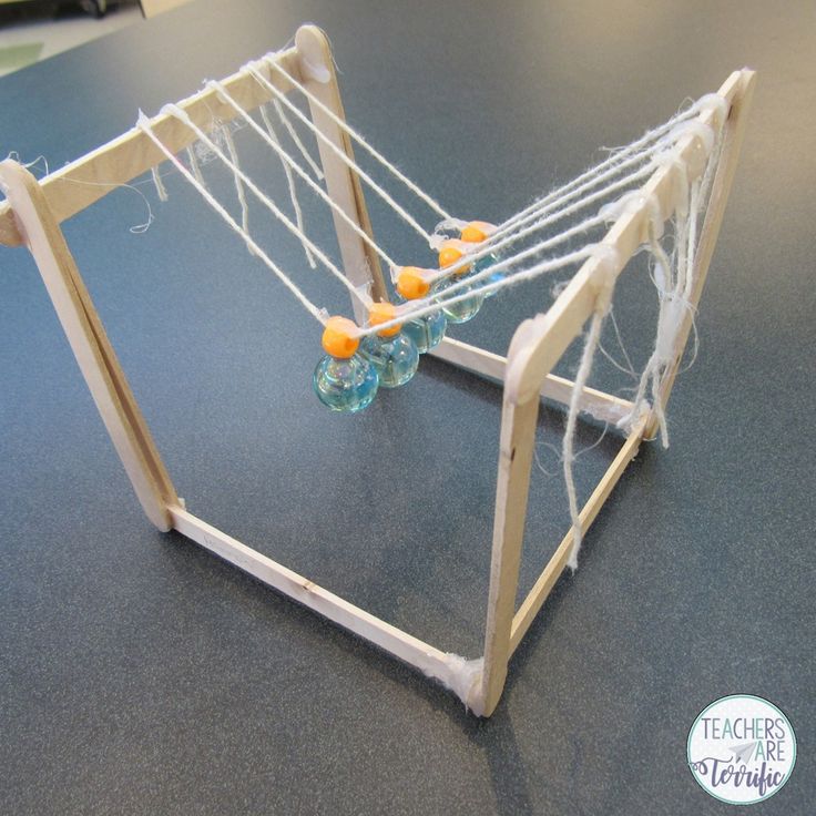 a wooden structure with strings and balls in it on a blue tableclothed surface