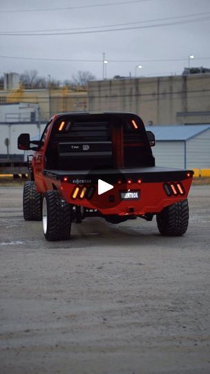 a red truck parked in a parking lot with lights on it's back end