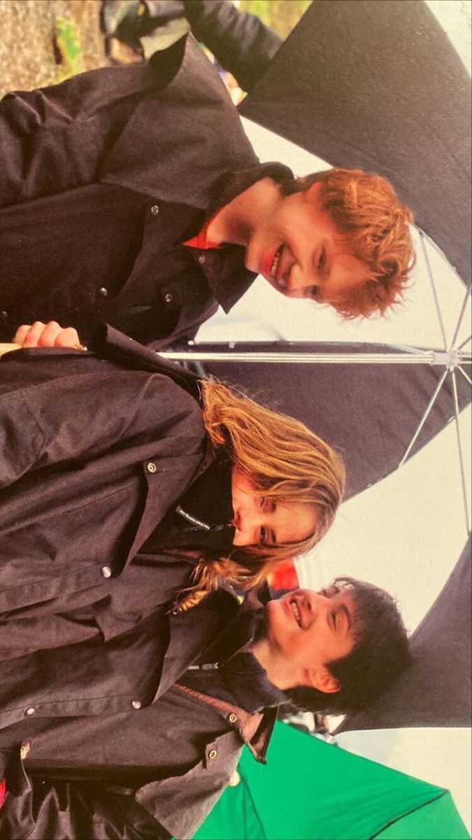 two men standing next to each other under an umbrella