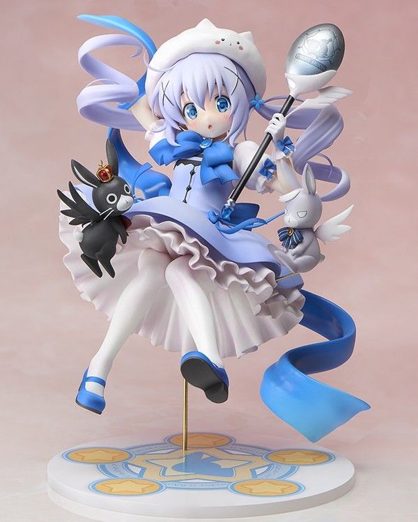 an anime figurine is posed on top of a stand with a cat and other items