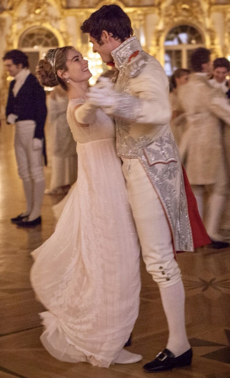 a man and woman dance together in an ornate room with other people dressed in white