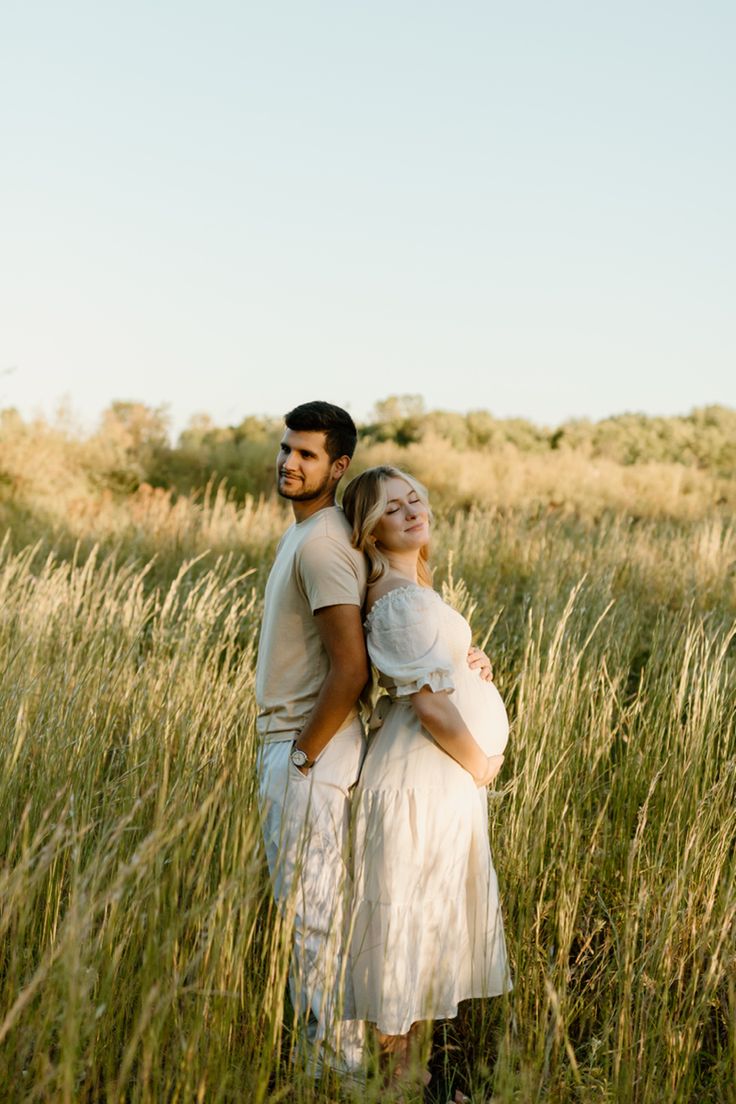 a man and woman are standing in the tall grass with their arms around each other