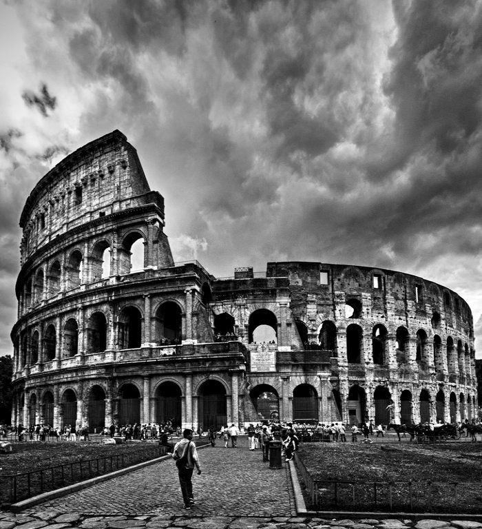 black and white photograph of the colossion in rome, italy with people walking around